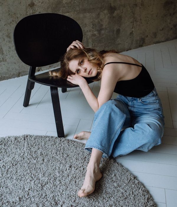 Person in a dynamic yet calm pose in a minimalist space.